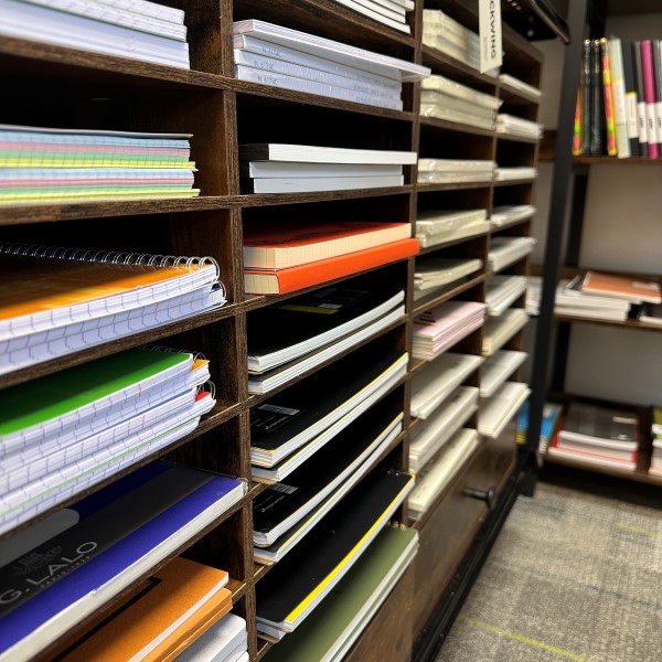 Closeup view inside The Gentleman Stationer shop of a shelf with notebooks and looseleaf papers in narrow cubbies.